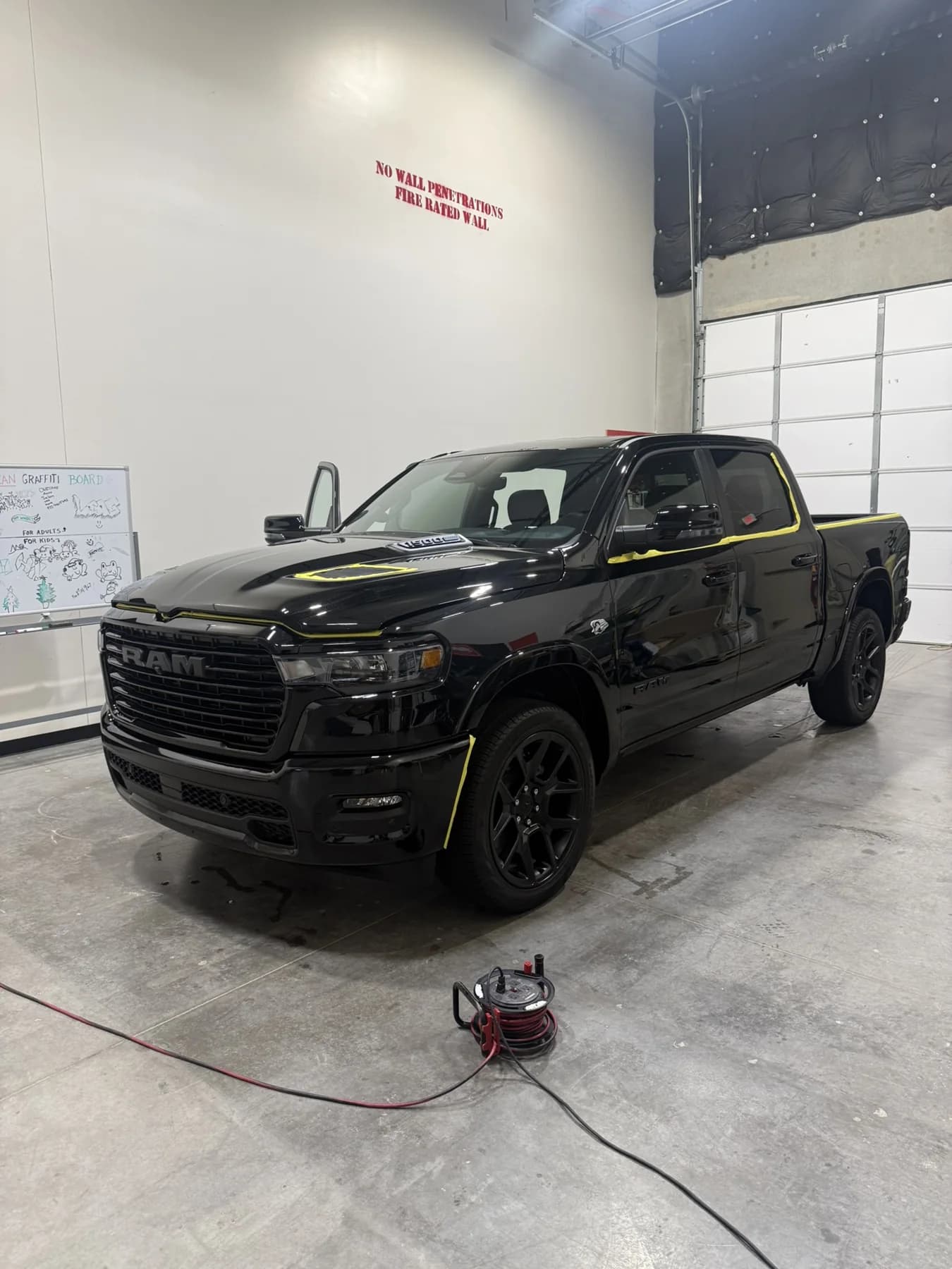 Black pickup with hood and door open during a detail